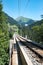 Narrow gauge railroad tracks lead over a long bridge in the Swiss Alps near Arosa
