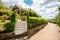 Narrow gravel lane beside red and white traditional allotment cabin with picket fence and flowers. Location Karlskrona in Sweden