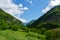 Narrow green valley between hills in Pyrenees mountains under the vivid cloudscape in France. Vivid tranquil landscape. Gorge