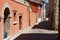 Narrow historical street with red painted bindings facades in Rimini, Italy.