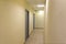 A narrow light corridor in the office room with a few gray doors