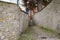 Narrow passage to a residential building between two stone walls is lined with paving stones