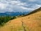 Narrow path on an autumn mountain slope. Footpath through valley in highland in sunny day. Hiking path. Spectacular view of