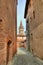 Narrow paved street among houses in Saluzzo.