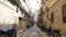 Narrow pedestrian greek street between old buildings in Lefkada town, Greece. Stock. Narrow street between houses with