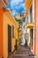 Narrow pedestrian street between buildings with colorful walls in seaside small town Scilla, old medieval castle Castello Ruffo