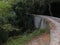 Narrow railway trail curves over the stone bridge in the forest