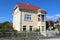 Narrow renovated urban family villa with new facade and roof tiles surrounded with white picket fence and garden vegetation