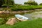 A narrow river channel in which a lotus blooms and a boat stands. Around the green lawns and landscaped area