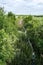 Narrow river flows through a field with trees to the horizon, a landscape background