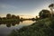 Narrow river summer scenery landscape with tranquil water mirror at sunset with clear sky and reflections riverbank