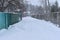 A narrow road poorly cleared of snow between the fences of the estates.