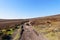 Narrow rock strewn footpath winds up hill on Derwent Moor