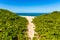 Narrow sand path to the beach and blue ocean