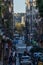 Narrow street in Barcelona, crowded with people walking on the sidewalk with bicycles and a lot of traffic at dawn