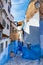 Narrow street of Chefchaouen city in Morocco with blue walls and pretty windows vertical