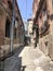 Narrow street, lane, tunnel with old houses, buildings on the sides in a poor area of the city, slums. Vertical photo