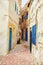 Narrow street of the old city with beige and white walls of the residential houses.