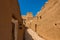 A narrow street in the traditional Arab mud brick village with a view on the Munikh Castle