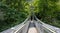 Narrow suspension bridge over Pineios River. Greece, Tempi Vale, Thessaly. Tree foliage background