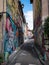 Narrow, urban street with colorful graffiti adorning the walls of the aged buildings in Toulouse.