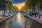 Narrow water canal with boats at sunset in Amsterdam, Netherlands
