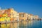 Narrow water canal with promenade embankment and colorful buildings in Chioggia