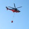 Narva, Estonia - 27 July 2018: A helicopter of the fire service with a fire fighting bucket is taking part in putting