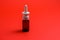 Nasal spray in dark bottle with nozzle on red background.