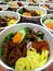 Nasi kuning bowl with shredded eggs, shredded fried chicken, kering tempe and kentang balado