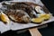 National dish of river fish. Grilled carp, crucian carp with lemon slices and salt on a wooden board and craft paper