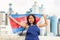 National flag of Cambodia in the hands of girl in overalls against background of modern metallurgical plant