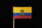 A national flag of Ecuador on toothpick on black background. A horizontal tricolor of yellow, blue and red with the national coat