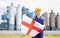 National flag of England in the hands of girl in overalls against background of modern metallurgical plant