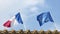 The national flag of France and the flag of the European Union against a blue sky