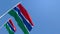 The national flag of Gambia is flying in the wind against a blue sky