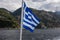 National flag of Greece waving in wind. Scenic view from tourist boat on Osiou Gregoriou Monastery at Mount Athos, Chalkidiki,