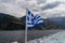 National flag of Greece waving in wind. Scenic view from tourist boat on Osiou Gregoriou Monastery at Mount Athos, Chalkidiki,