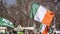 National Flag of Ireland close-up above the people crowd people, traditional carnival of St. Patrick`s Day