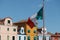 National flag of Italy fly above Burano island main piazza square. Island with colorful painted houses