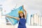 National flag of Kazakhstan in the hands of girl in overalls against background of modern metallurgical plant