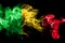 National flag of Mali made from colored smoke isolated on black background. Abstract silky wave background.