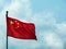 National flag of the Peope`s Republic of China flying at full mast against a light blue sky