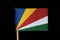 A national flag of Seychelles on toothpick on black background. Consists from five oblique bands of blue, yellow, red, white and g