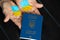 The national flag of Ukraine is drawn on the hands of a woman and next to a foreign passport on the table, stop war and