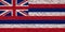 The national flag of the US state Hawaii in against a gray wall with stony surface on the day of independence in color of blue red