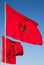 National flags of Morocco above blue sky