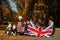 National holiday of United Kingdom. Family with british flags in autumn park.  Britishness celebrating UK. Mother with four kids