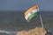 National table flag of India on sea background. Flag of India on sandy shore