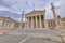 National university classical building facade with Athena and Apollo statues on Ionian style columns under impressive sky.